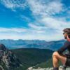 A man sits on rocky terrain, enjoying a scenic mountain view., tags: für und - pexel