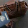 Brown leather bag with passport in an airport setting, ideal for travel and fashion themes., tags: und reisen - pexel