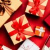 Top view of beautifully wrapped holiday gifts with red and brown ribbons on a vibrant red background., tags: durchdachte - pexel